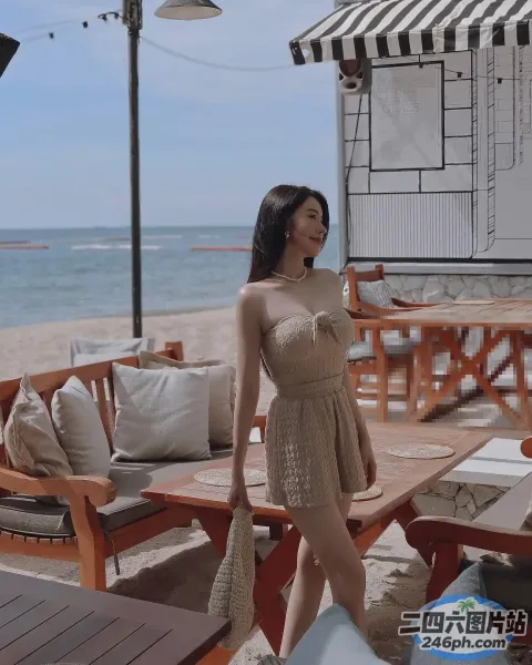 海滩上站着一个女人，手里拿着手机