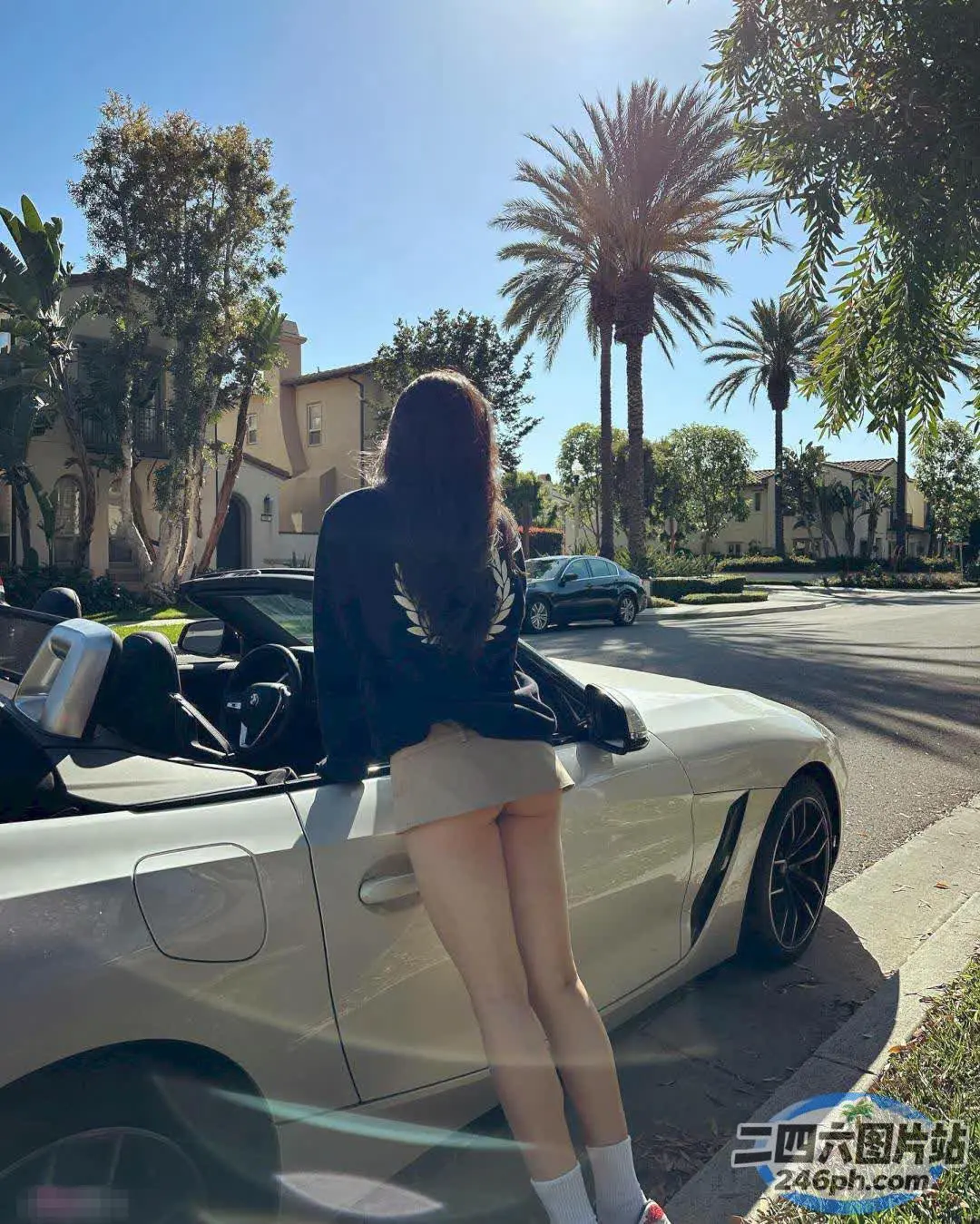 阿拉菲坐在街上一辆跑车的引擎盖上