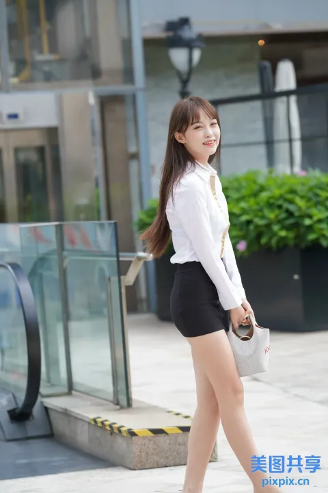 一名身穿短裙和白衬衫的女子走在人行道上