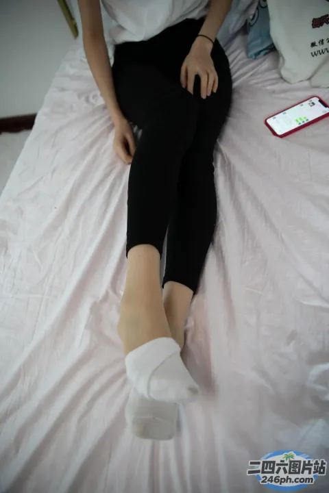 有一个女人坐在床上，双脚抬起