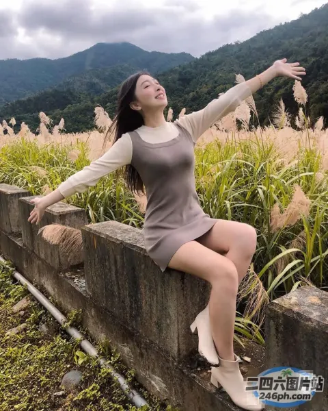 一个女人坐在墙上，双臂伸向空中