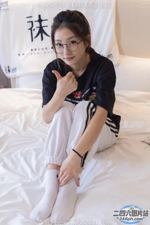 阿拉伯裔亚洲妇女坐在铺着白色床单的床上