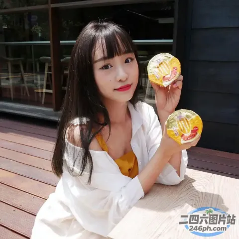 有个女人坐在桌子上，手里拿着两个甜甜圈