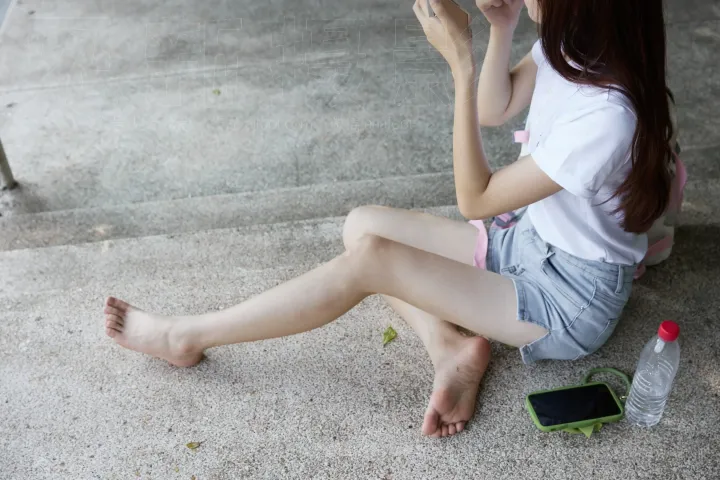 地上坐着一个女人，手里拿着手机