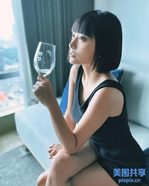 阿拉菲女人坐在沙发上，手里拿着一杯酒