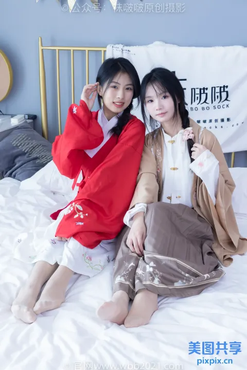 两名亚裔女性坐在卧室的床上