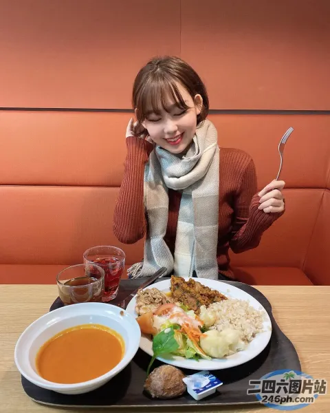 女人坐在桌子旁，手里拿着一盘食物和一碗汤