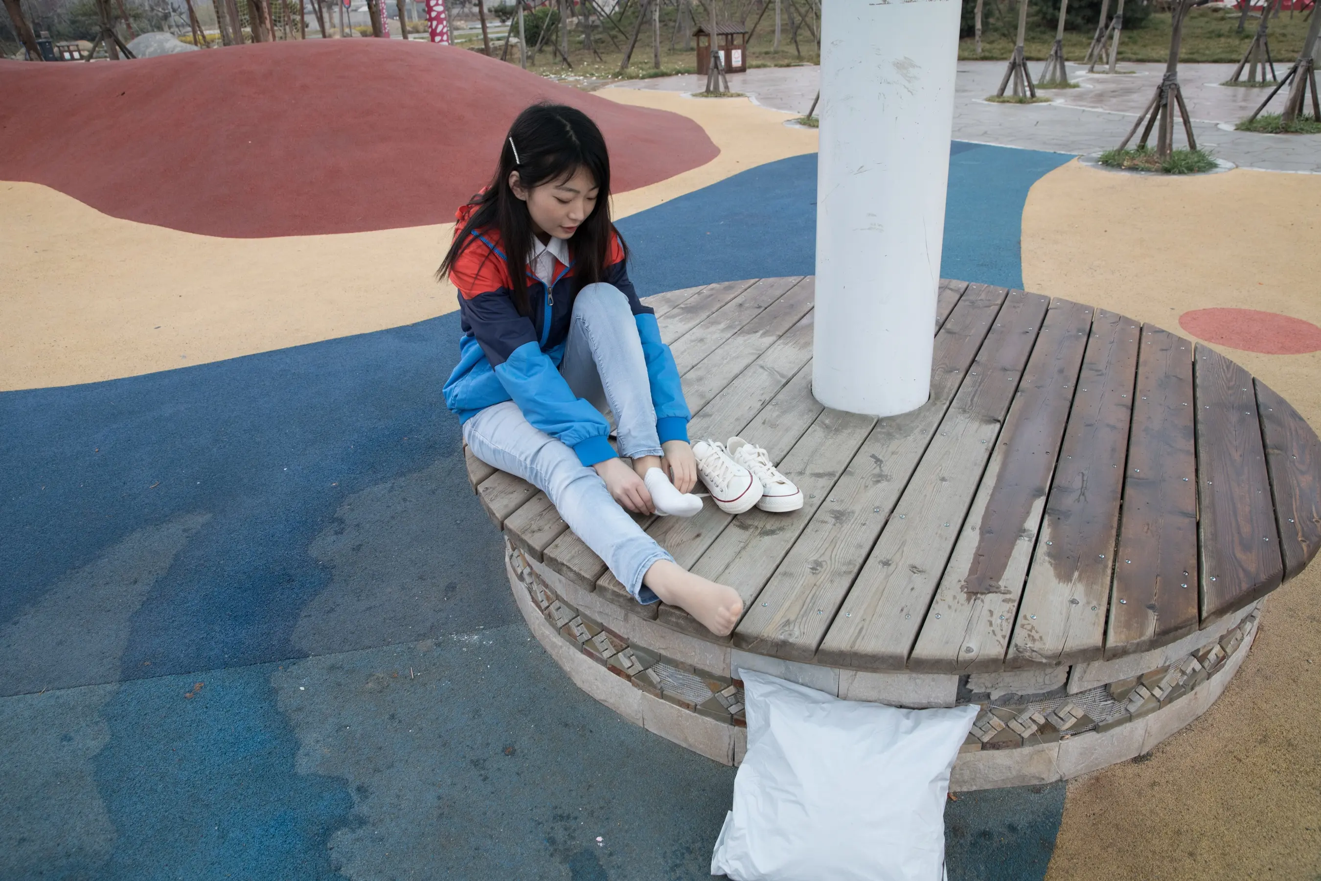 公园里的木凳上坐着一个年轻女孩