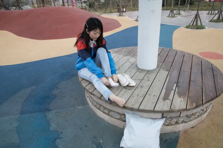 公园里的木凳上坐着一个年轻女孩