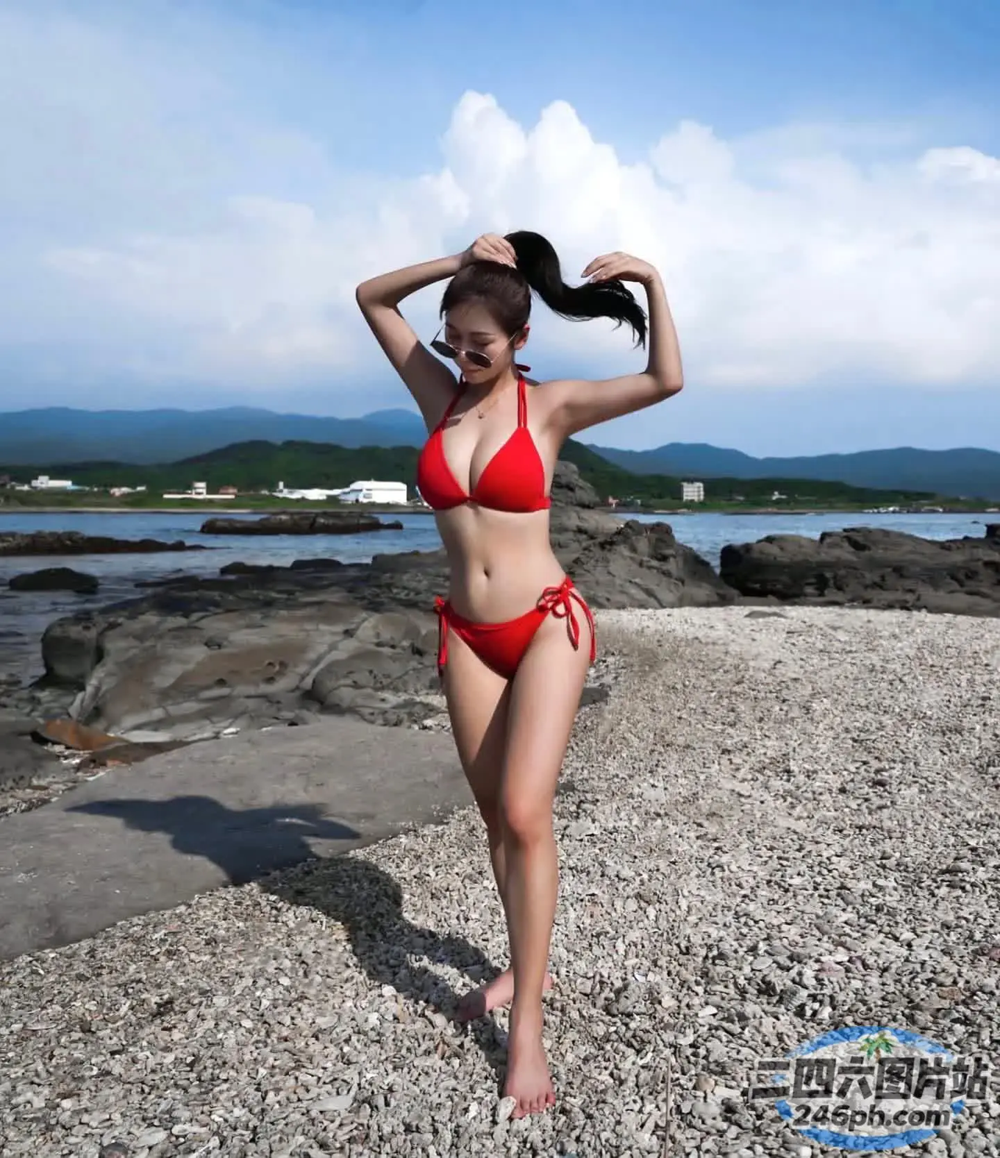 身穿红色比基尼的 arafed 女子站在岩石海滩上