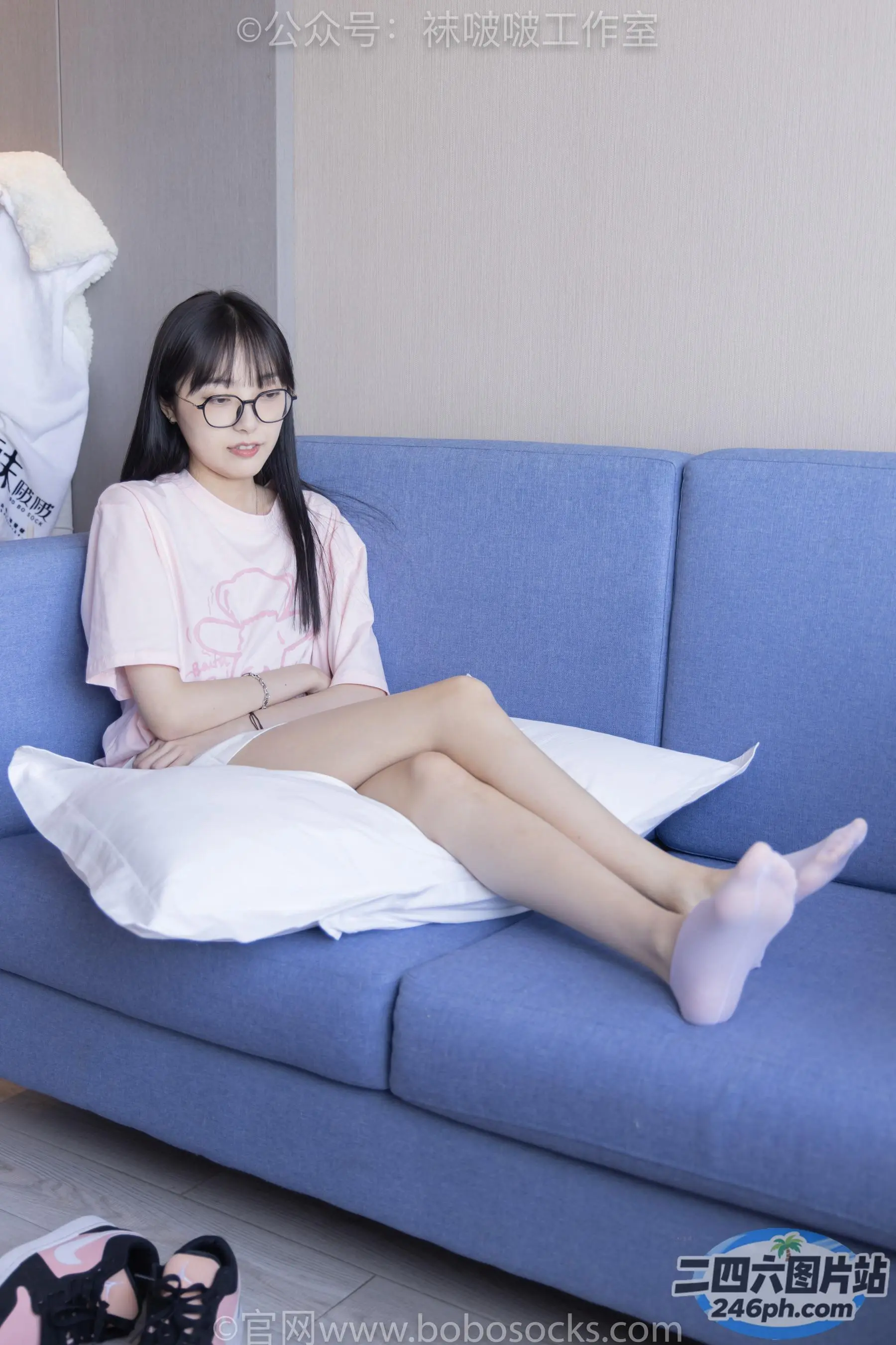 阿拉菲德亚洲妇女坐在蓝色沙发上，双腿交叉