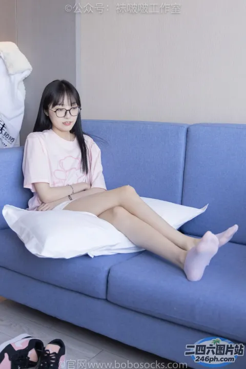 阿拉菲德亚洲妇女坐在蓝色沙发上，双腿交叉
