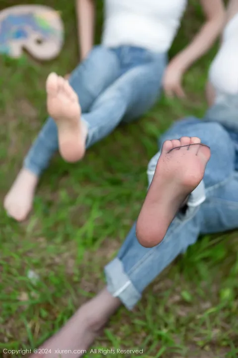 有两个女人坐在草地上，脚抬起来