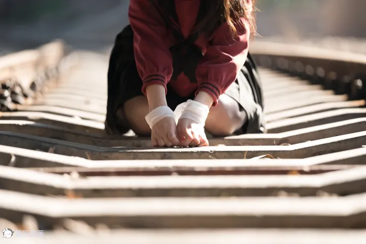 有一个女人跪在火车轨道上，手放在铁轨上