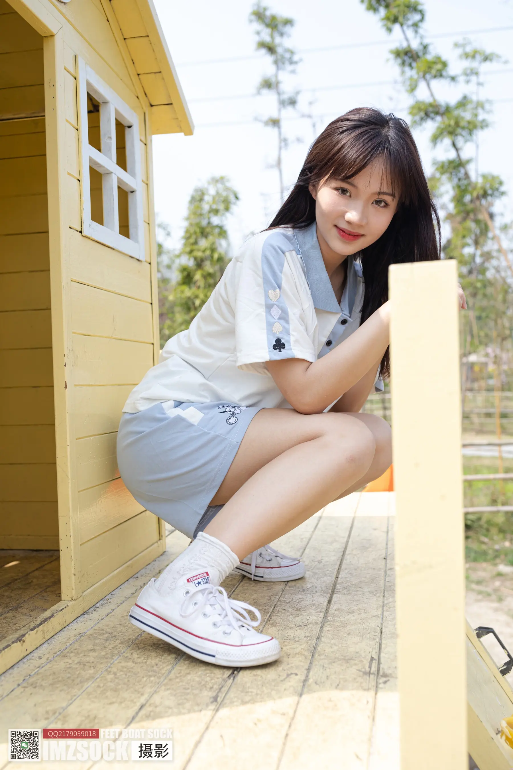 蹲在有狗屋的门廊上的阿拉菲女孩
