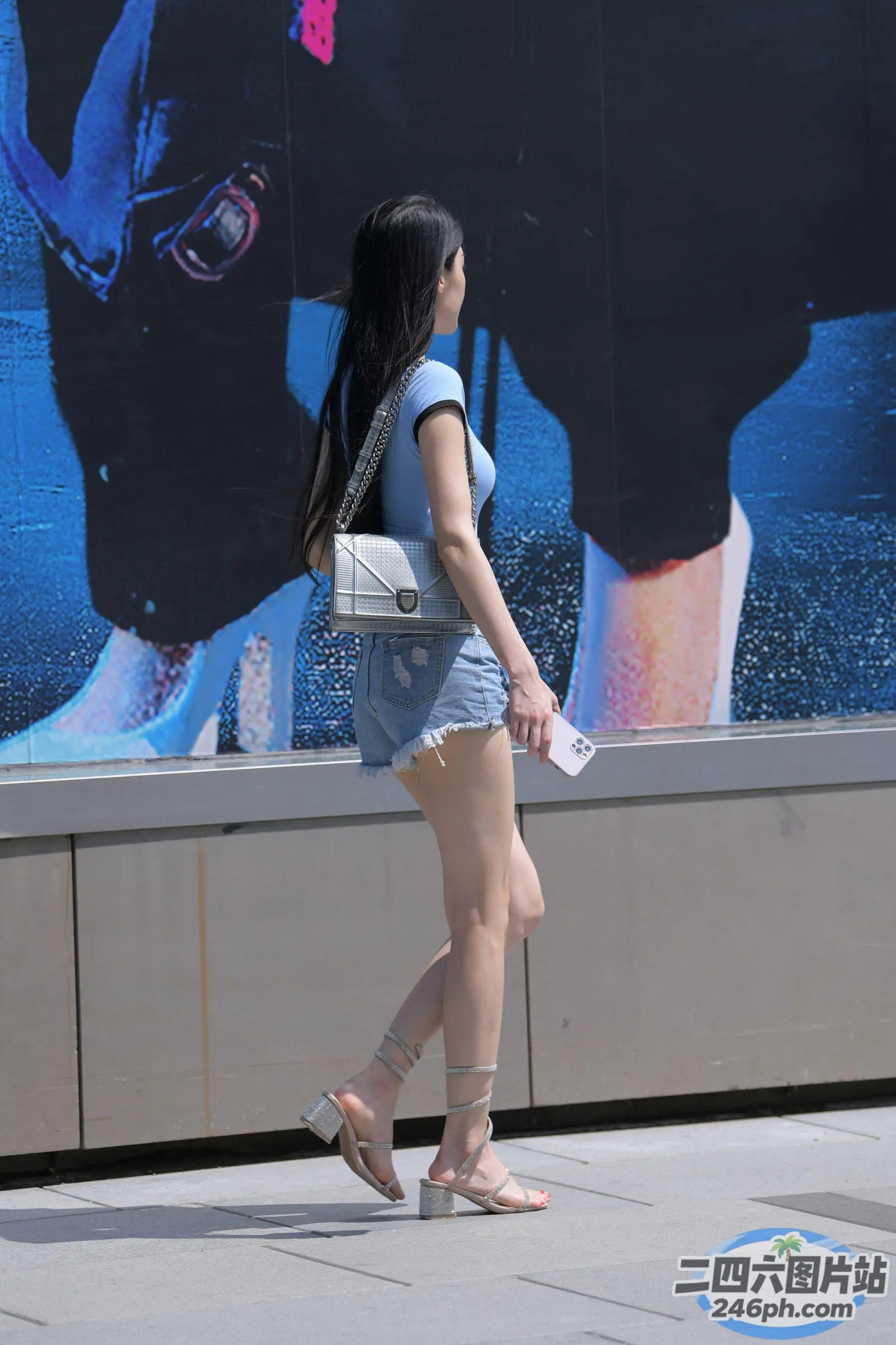 女子走在人行道上，站在建筑物上的大型广告前