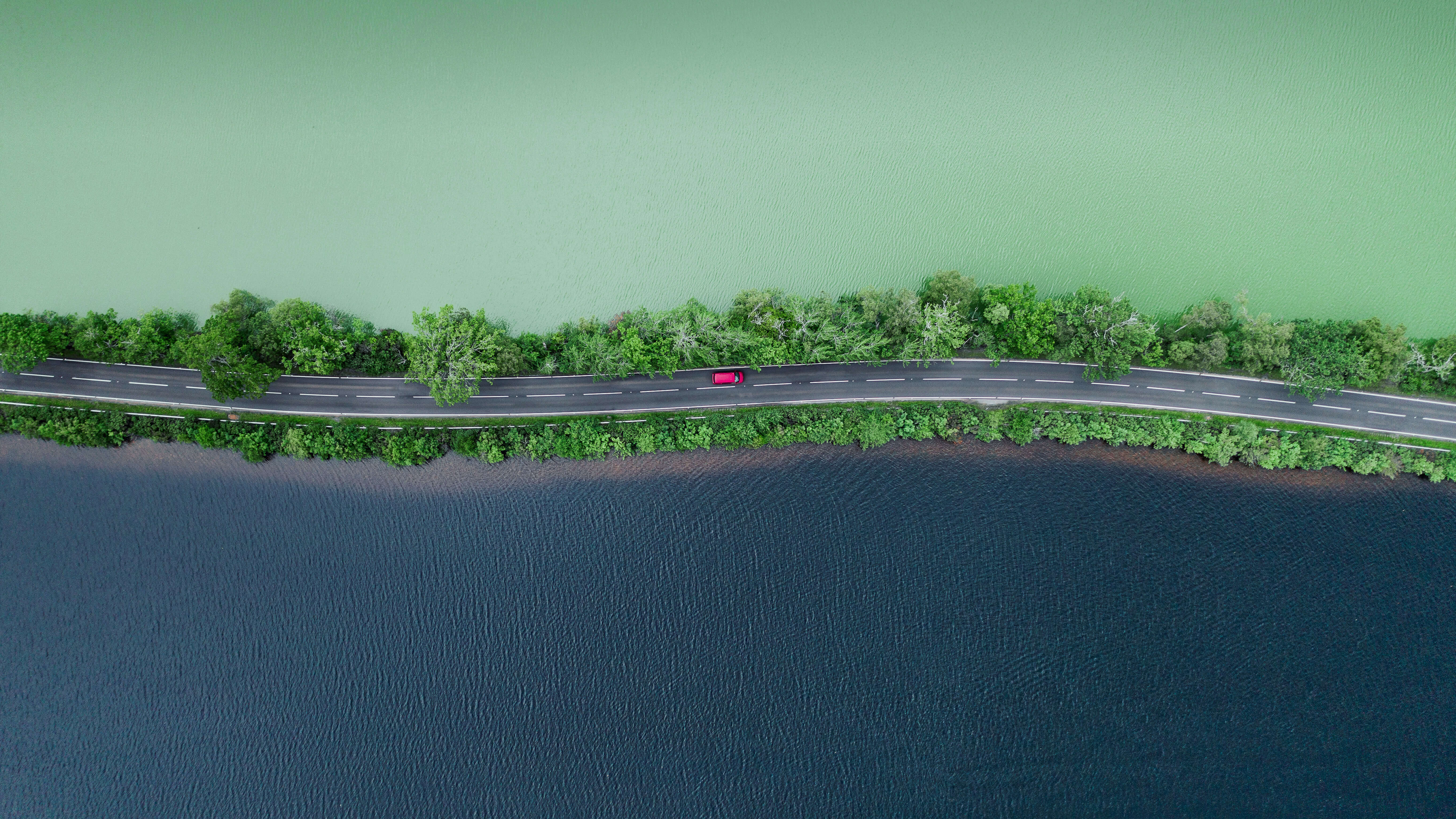 在水体旁边的道路上行驶的汽车的鸟瞰图