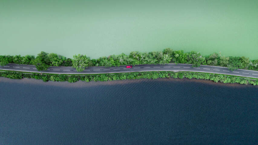在水体旁边的道路上行驶的汽车的鸟瞰图