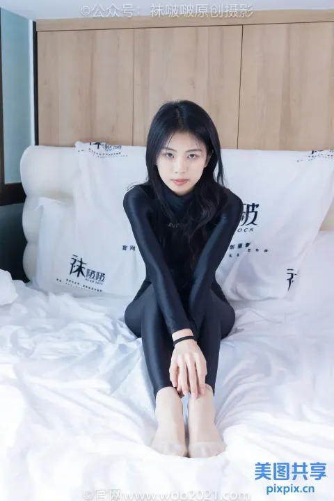 坐在床上穿着黑色潜水服的 Arafed 女人
