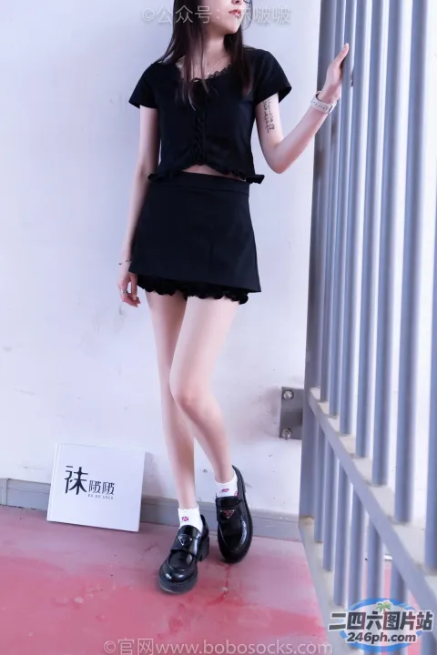 一个穿着黑色连衣裙和黑色鞋子的女人站在墙边