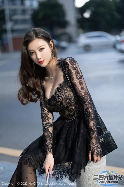 一名身穿黑色连衣裙的女子坐在水泥块上