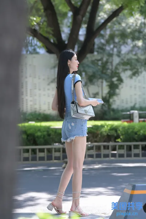 穿着牛仔短裤和背包的 araffe 女人走在街上