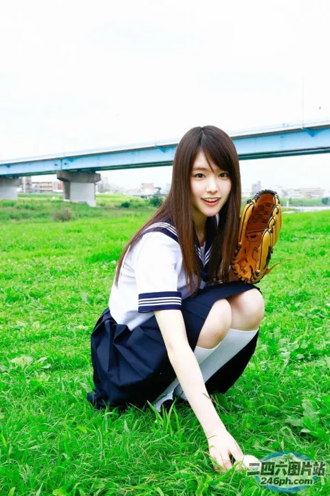身穿制服的 Arafed 亚洲女孩戴着棒球手套跪在田野上