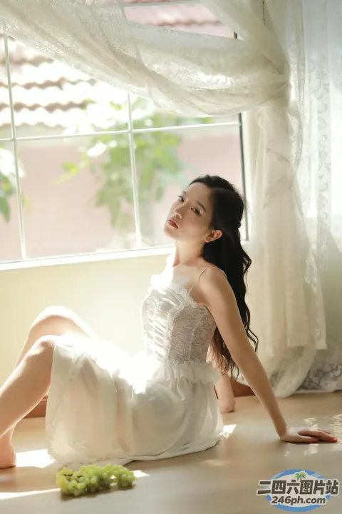 地板上坐着一个穿着白色连衣裙的女人