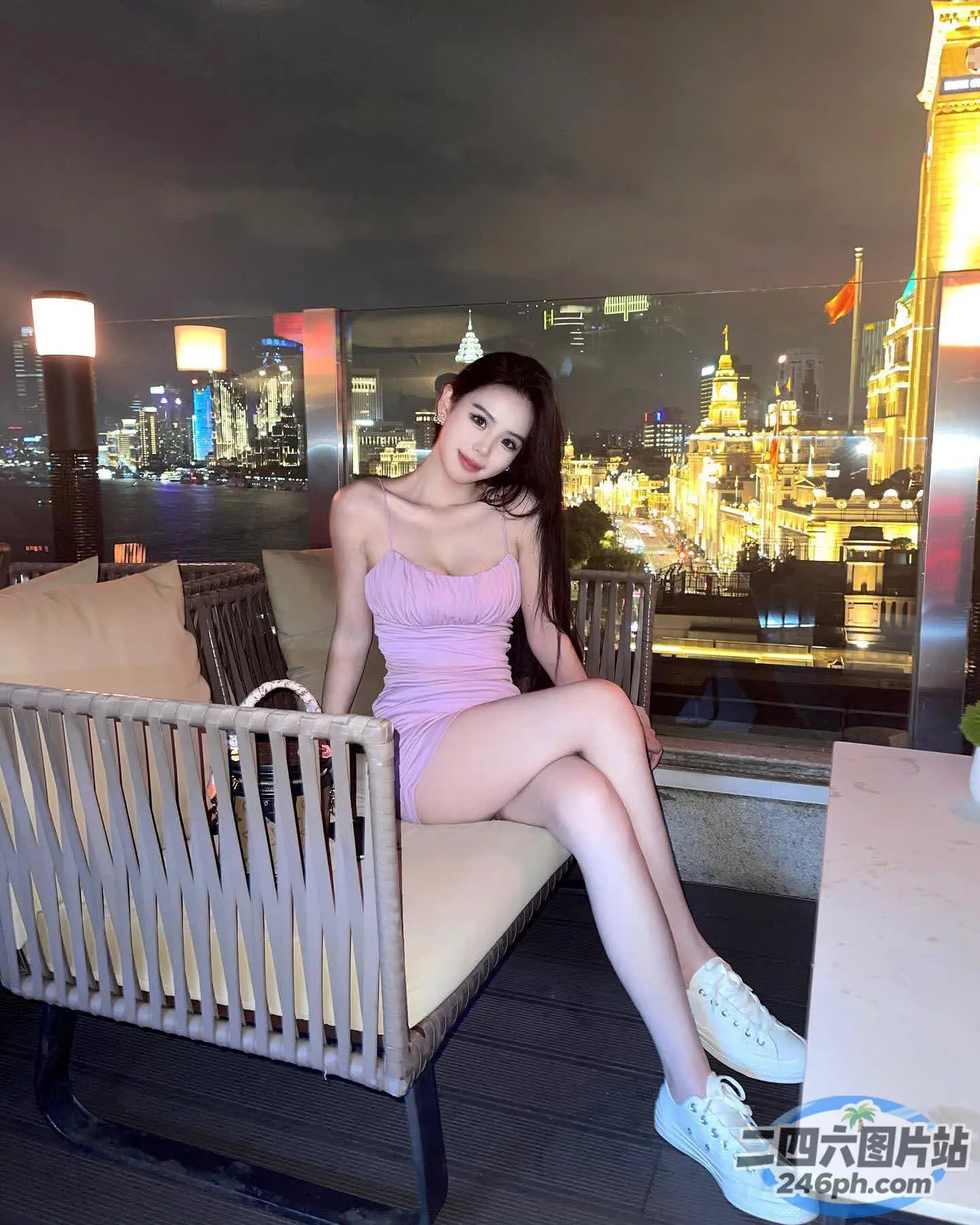 阿拉菲穿着粉红色的连衣裙坐在城市景观前的长凳上