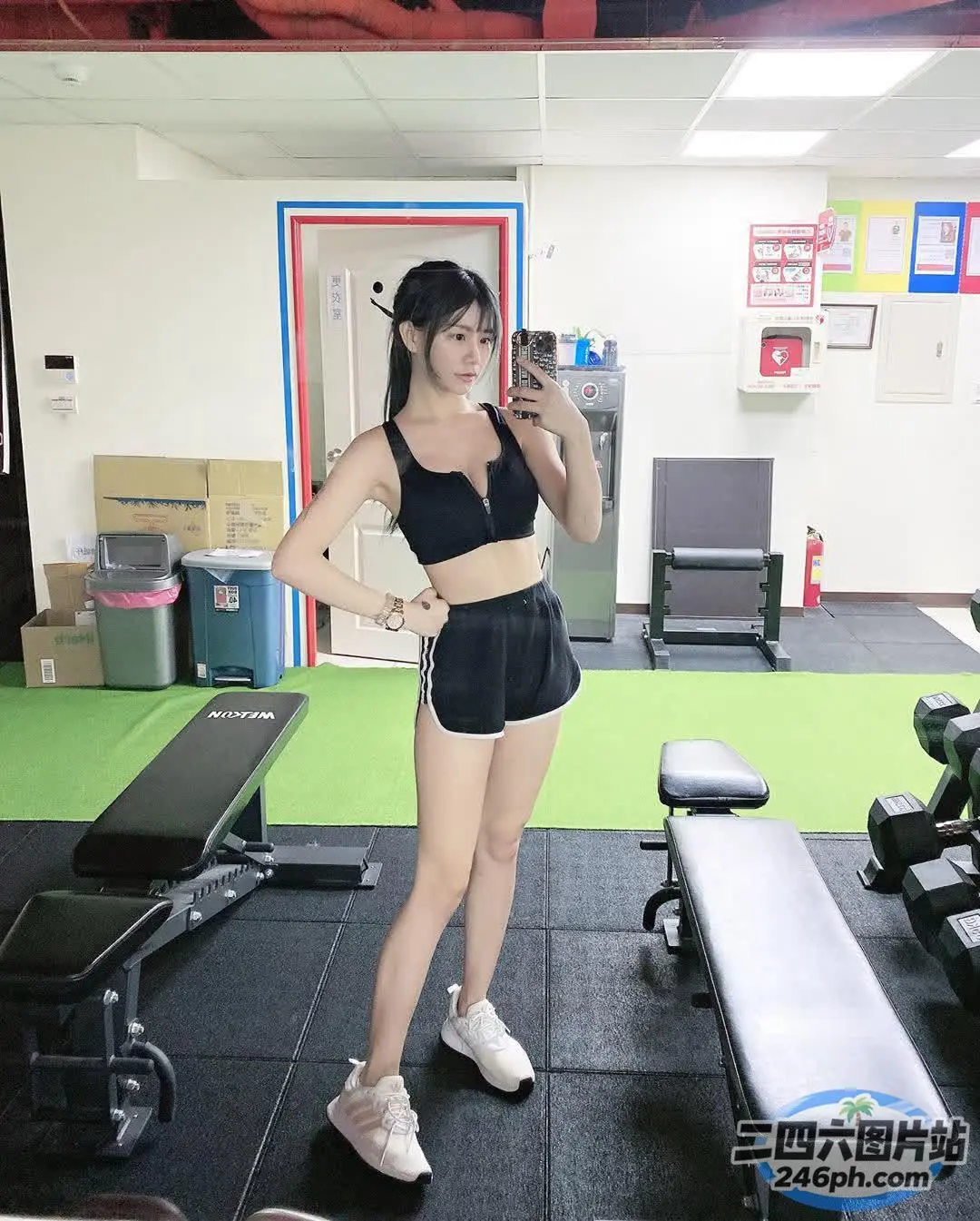 健身房里站着一个穿着黑色上衣和短裤的女人