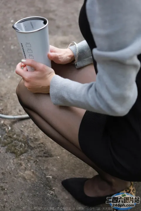 有一个女人跪下来，手里拿着一杯咖啡