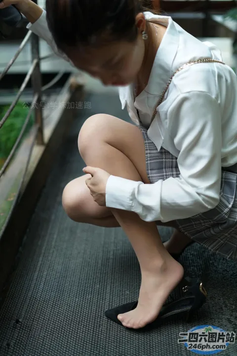 身穿校服的 arafed 亚裔妇女蹲在栏杆上