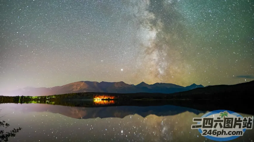 湖面上的星空，背景是露营车和一座山