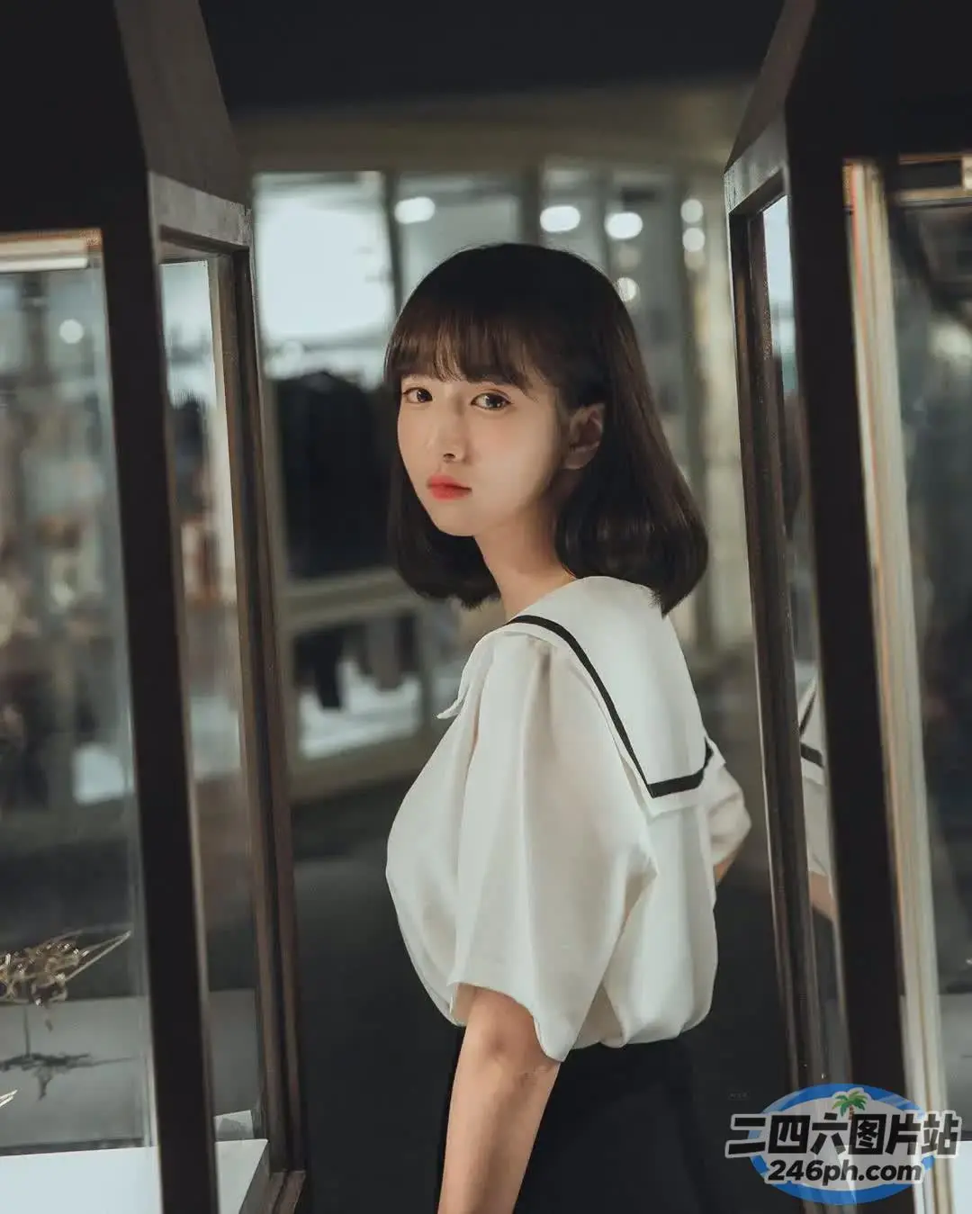 一个女人站在玻璃柜前，穿着白衬衫