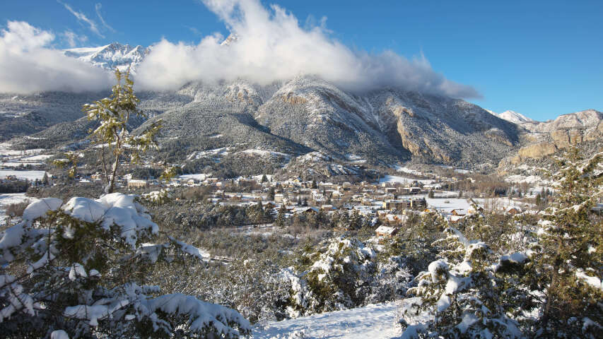 白雪皑皑的山峰，远处有一座小镇和几棵树