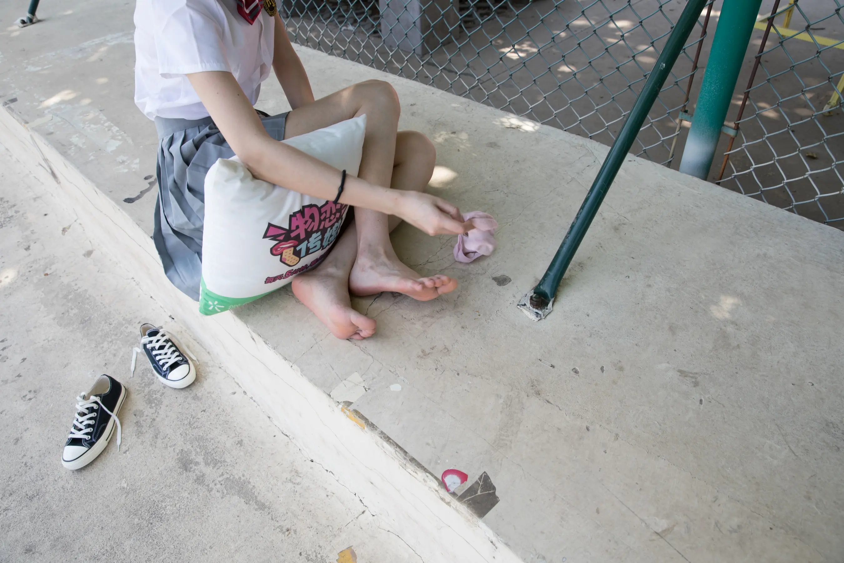 有一个小男孩坐在路边，双脚撑着