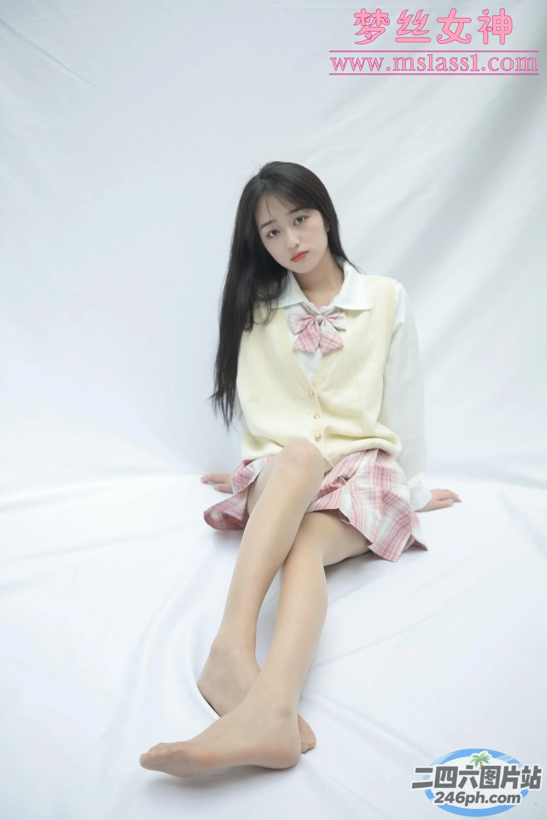 一个女人坐在床上的特写，床上铺着白色床单