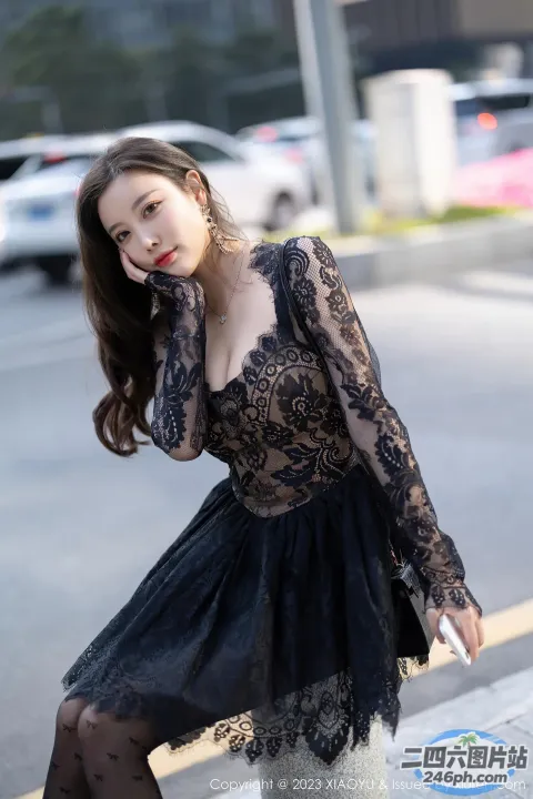 一名身穿黑色连衣裙的女子在街角摆姿势