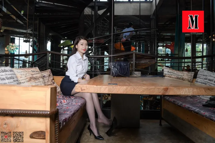有一位女士拿着笔记本电脑坐在桌子旁