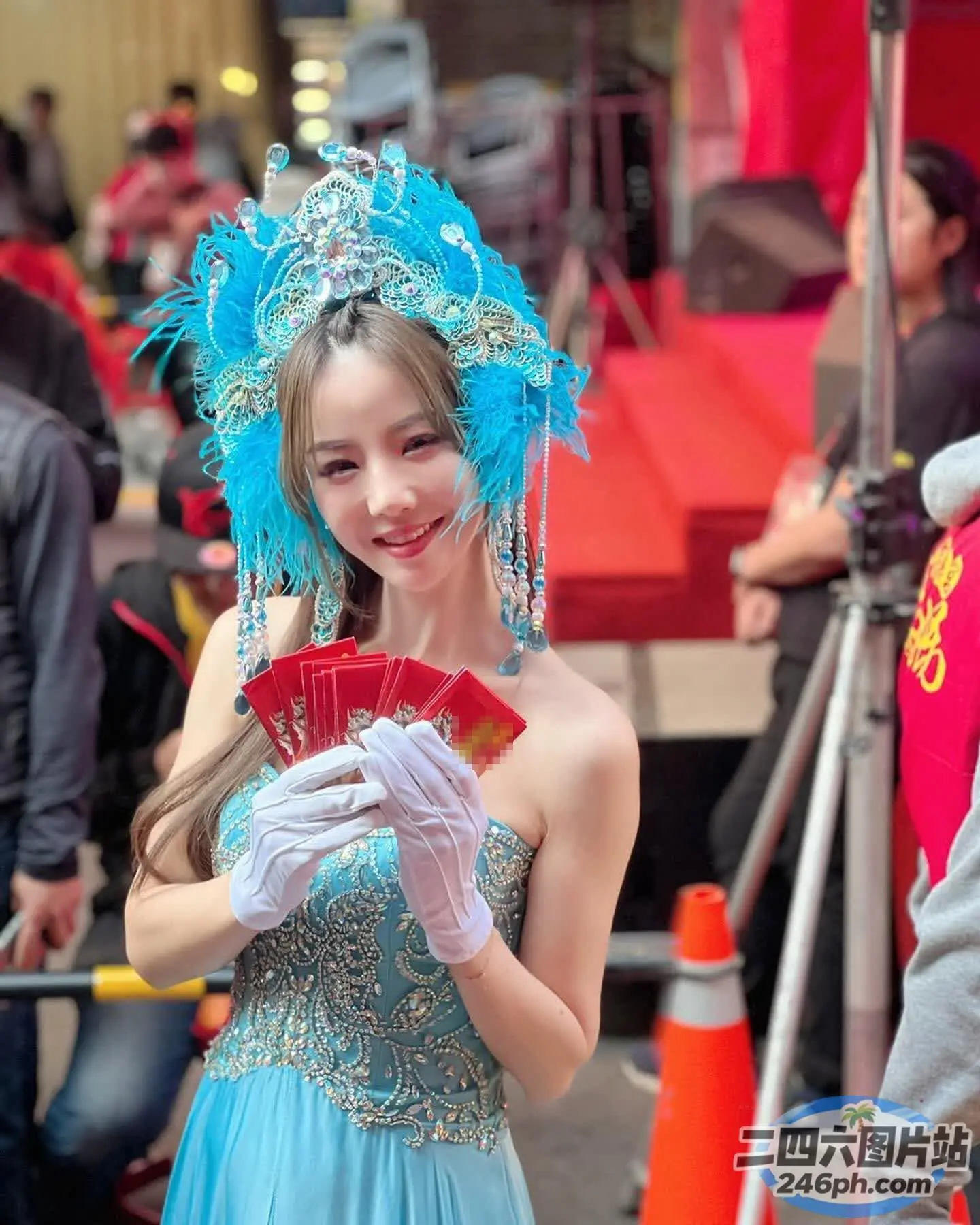 阿拉菲身穿蓝色连衣裙，手里拿着一把红色扇子