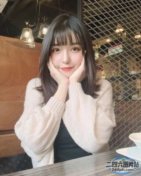 阿拉菲女人坐在桌子旁，手里拿着一杯咖啡