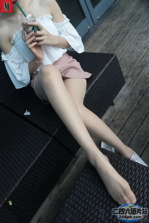 女人坐在长凳上，手里拿着饮料