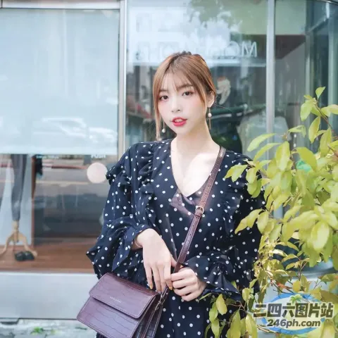 身穿波点连衣裙的阿拉伯女郎，手里拿着一个紫色的钱包