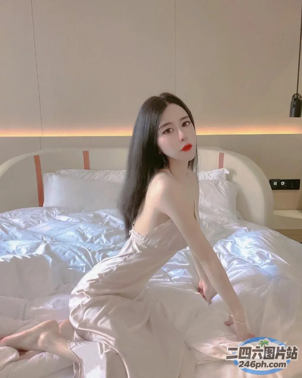 有个女人坐在一张铺着白色床单的床上