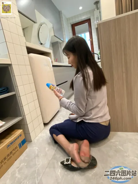 阿拉菲女人坐在厨房的地板上，手里拿着牙刷