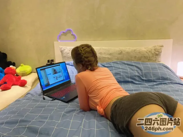 女人躺在床上，手里拿着笔记本电脑，床上放着毛绒玩具