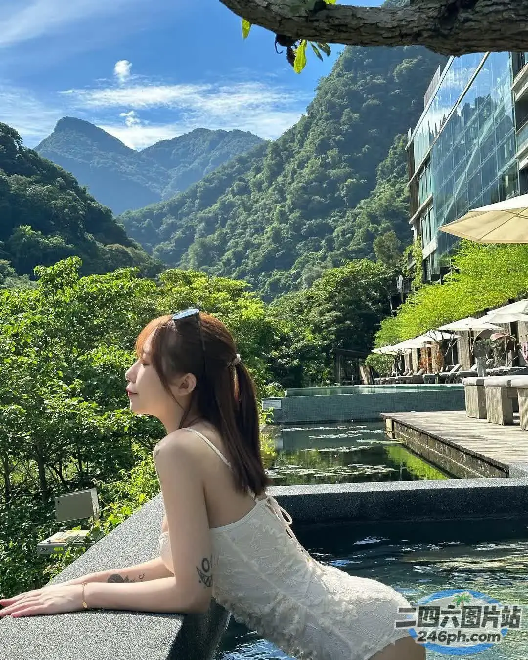 一位女士坐在窗台上，俯瞰着泳池和群山