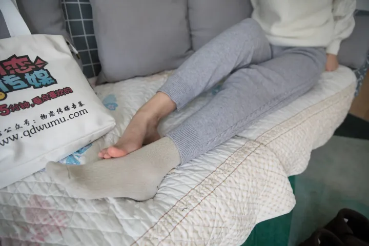 有一个女人坐在床上，腿上放着一个袋子
