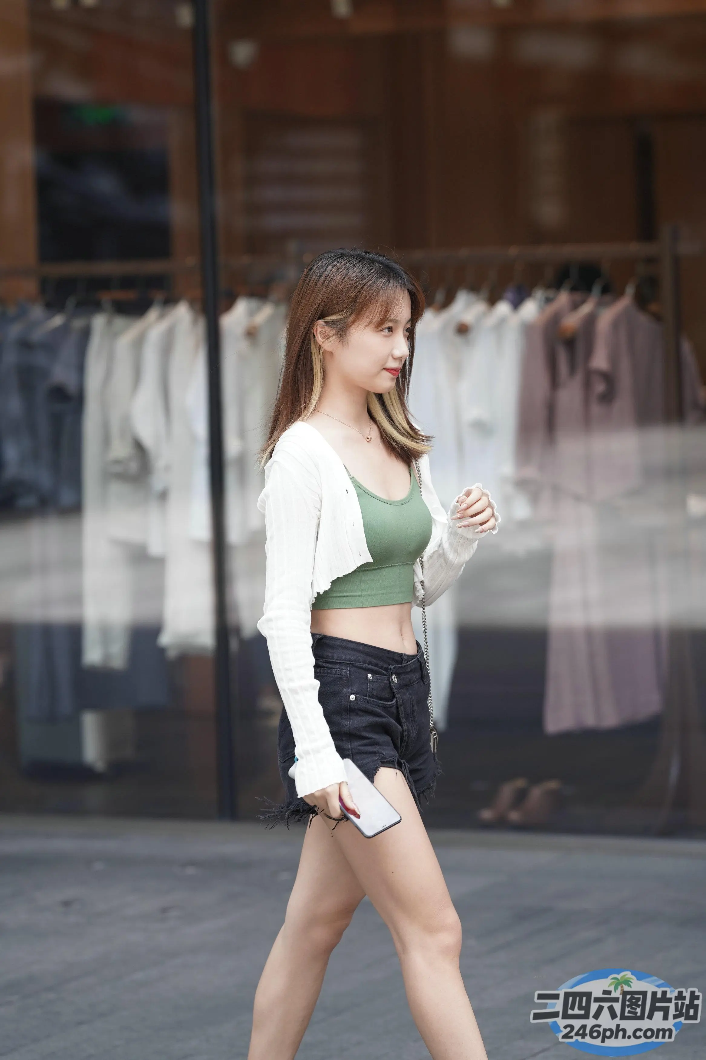 一名女子走在街上，经过商店的橱窗