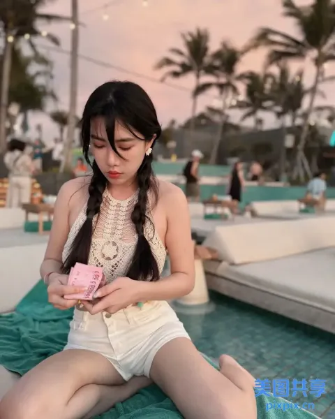 阿拉菲女子坐在毯子上，手里拿着一个粉红色的物体